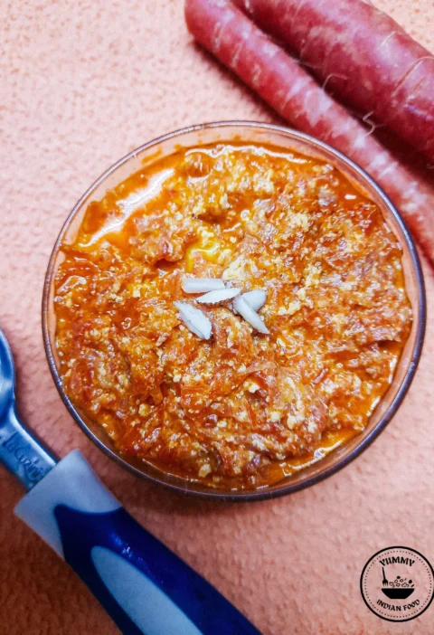 A bowl of rich, golden Gajar Ka Halwa topped with slivered almonds, exuding warmth and indulgence