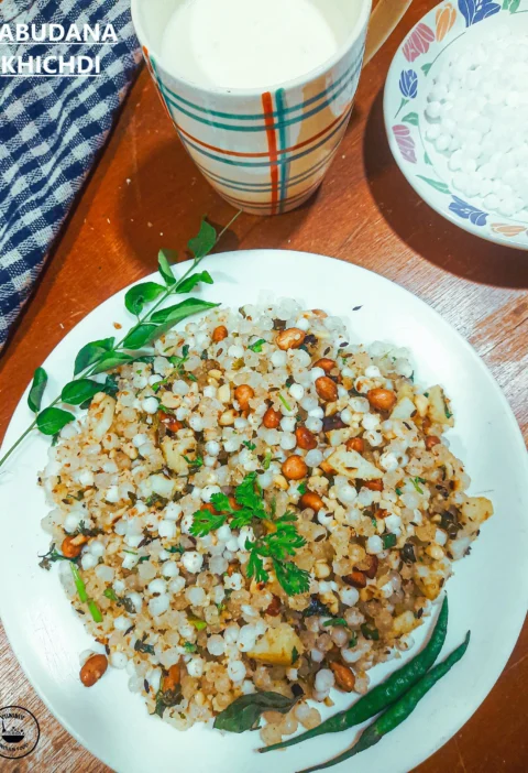 A plate of Sabudana khichdi for fast with fried chilies, accompanied by a cup of tea and a glass of milk.